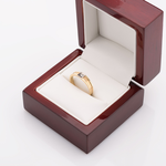 Złoty pierścionek z brylantem w pudełku.