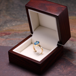 Złoty pierścionek z topazem w drewnianym pudełku.