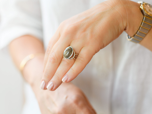 Srebrny pierścionek z krzemieniem pasiastym na palcu.