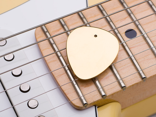 złota kostka do gitary - jako tło Fender Stratocaster